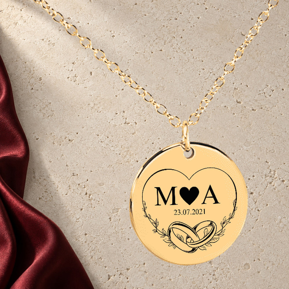 Collier Initiales Entrelacées Personnalisé (Eternal Love) en finition dorée sur pierre claire, avec étoffe rouge sanguine ; exemple de personnalisation.
