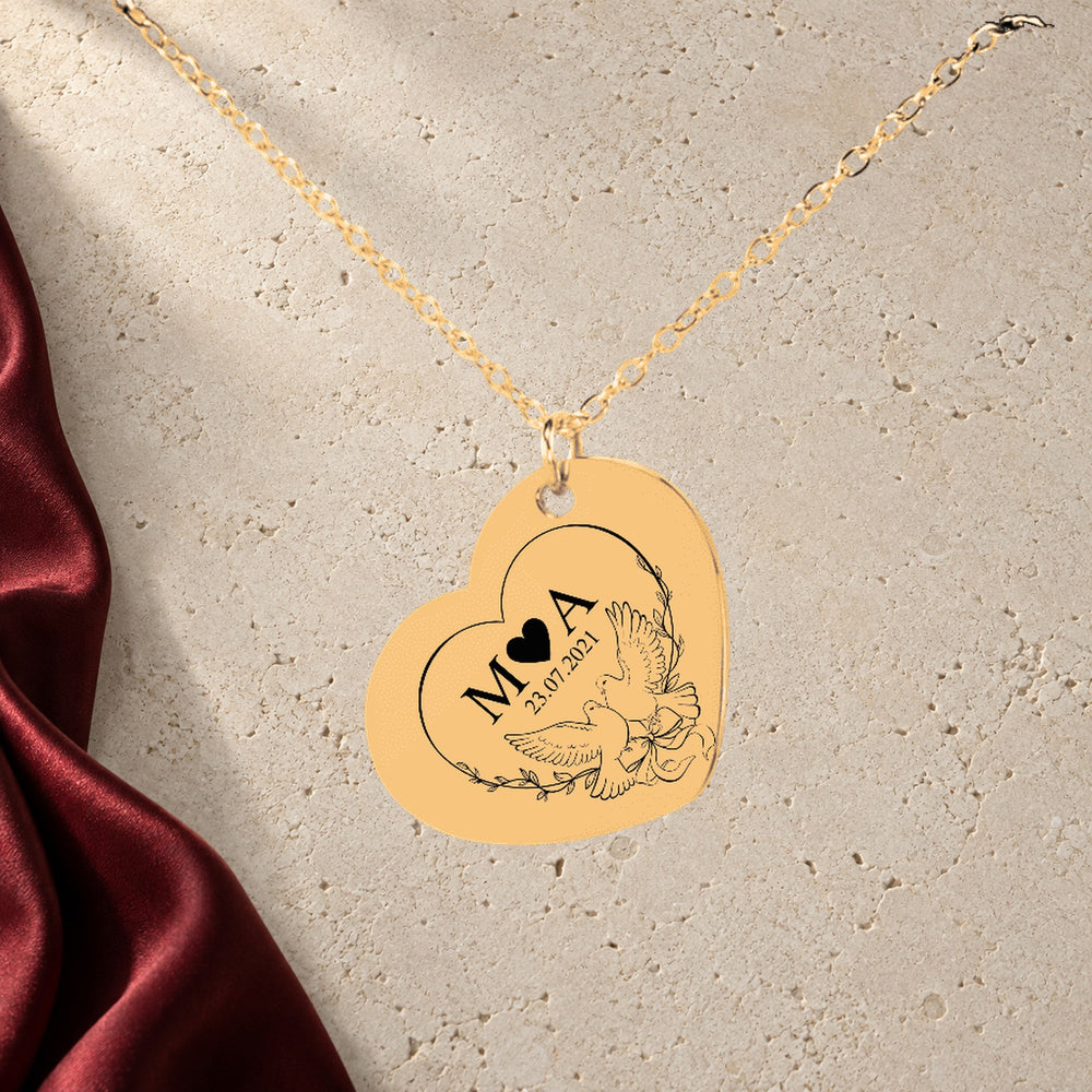 Collier Initiales Entrelacées Personnalisé (Eternal Love Coeur) en finition dorée sur pierre claire, avec étoffe rouge sanguine ; exemple de personnalisation.