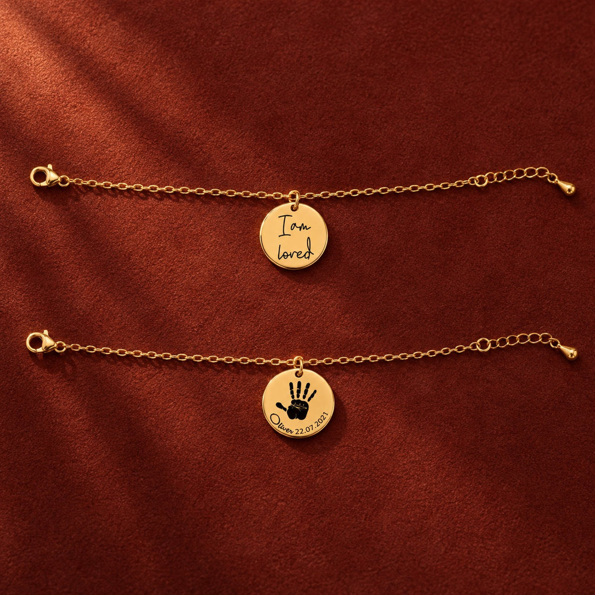 Deux bracelets chaîne dorés à médailles gravées, affirmation et empreinte de main, sur suédine rouge sanguine.