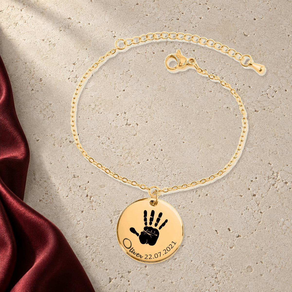Bracelet Empreinte de Main Réelle Gravée en finition dorée sur pierre claire, avec étoffe rouge sanguine ; exemple de personnalisation.