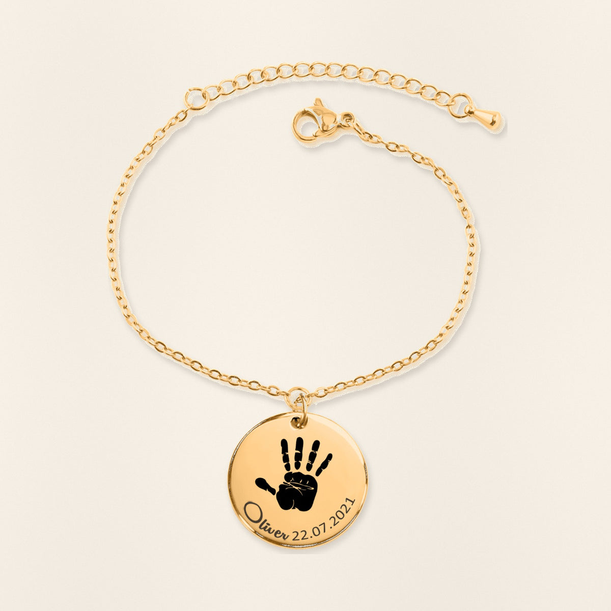 Bracelet Empreinte de Main Réelle Gravée en finition dorée, exemple de gravure sur fond ivoire texturé.
