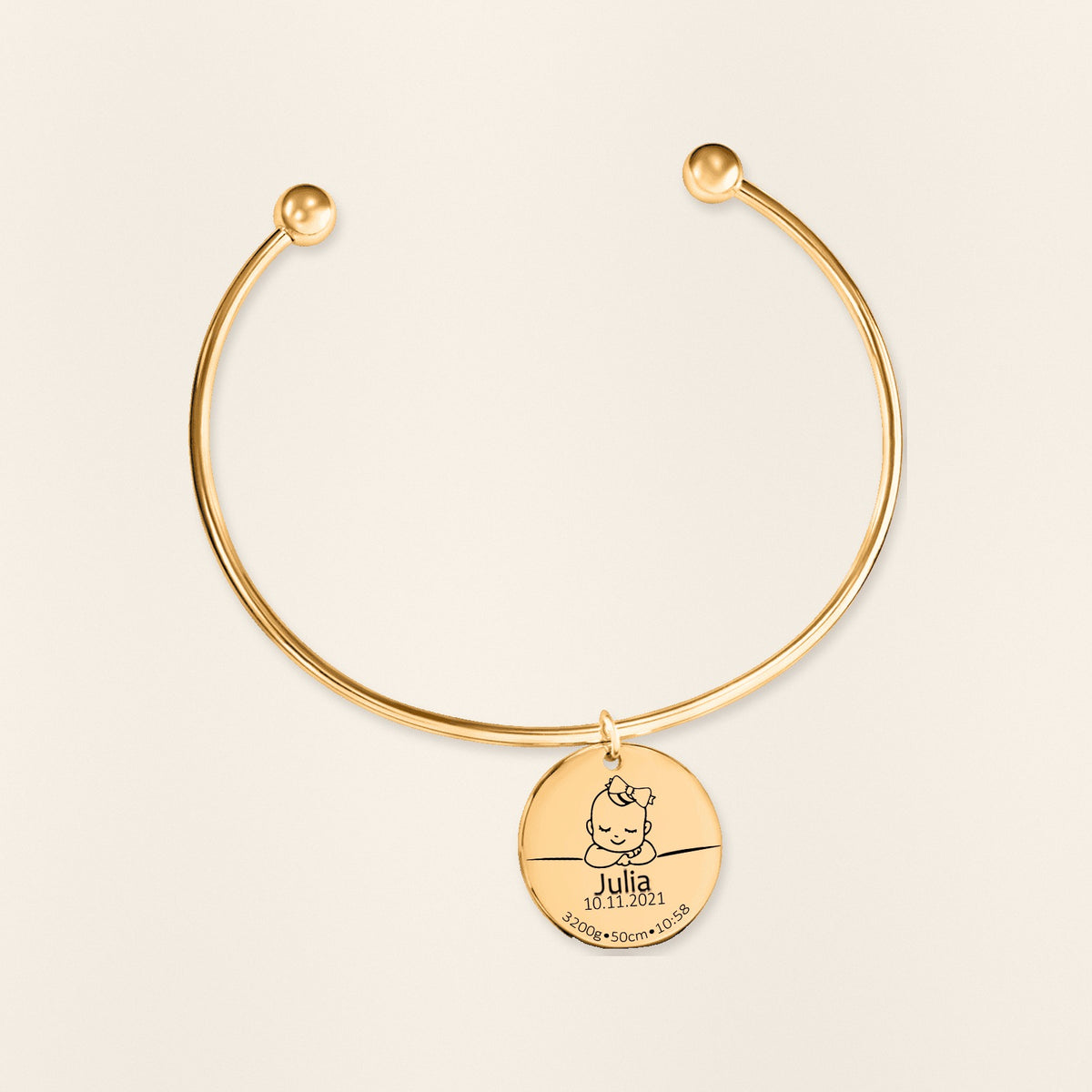 Bracelet jonc Détails de Naissance Personnalisés en finition dorée, exemple de gravure sur fond ivoire texturé.