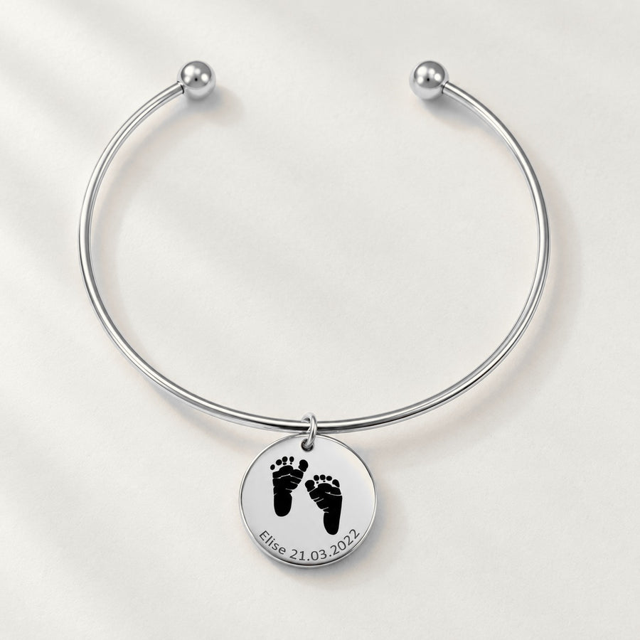 Bracelet jonc Empreinte de Pied Réelle Gravée, finition argentée, sur fond ivoire.