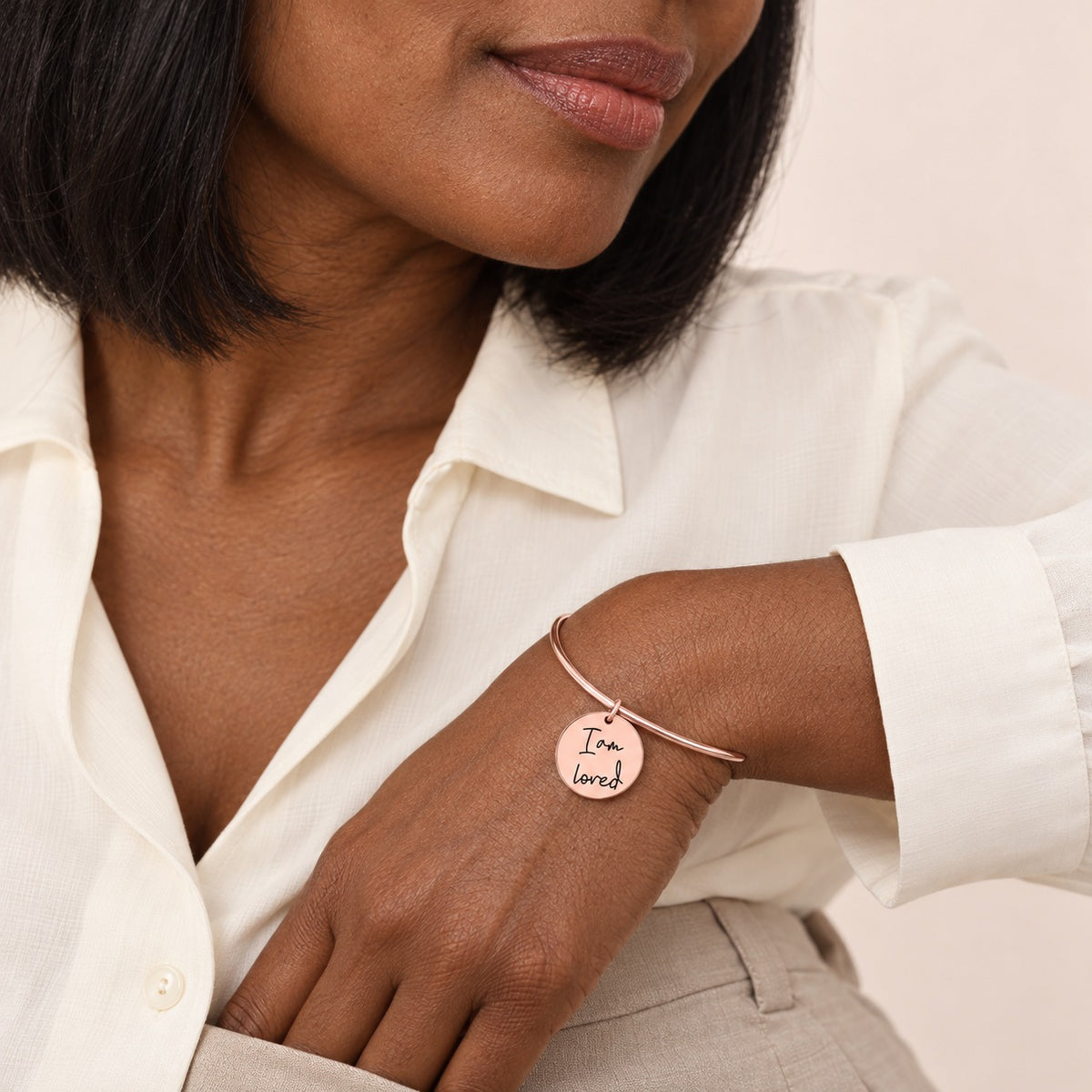 Bracelet jonc Médaille Affirmations Personnalisée, finition or rose, porté au poignet.