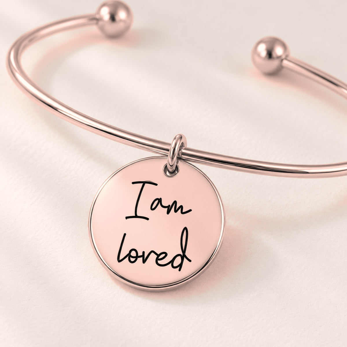 Bracelet jonc Médaille Affirmations Personnalisée, finition or rose, en gros plan sur la gravure.