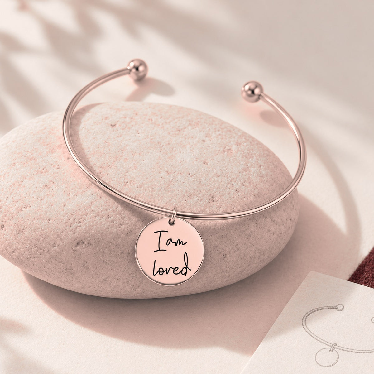 Bracelet jonc Médaille Affirmations Personnalisée, finition or rose, sur une pierre claire.