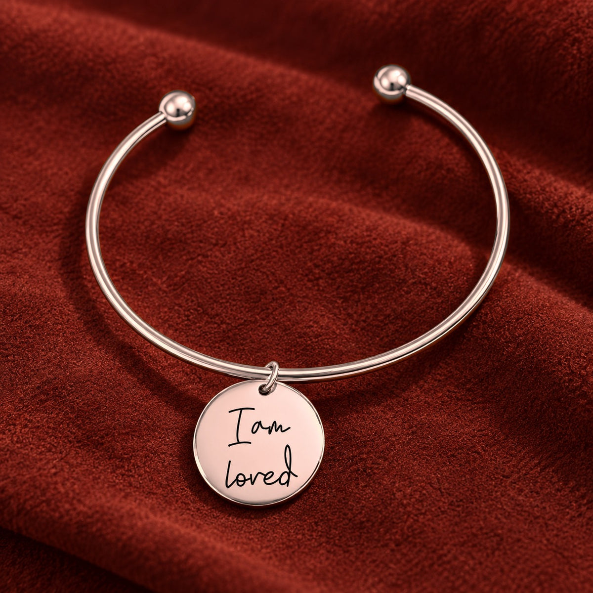 Bracelet jonc Médaille Affirmations Personnalisée, finition or rose, sur fond rouge sanguine.