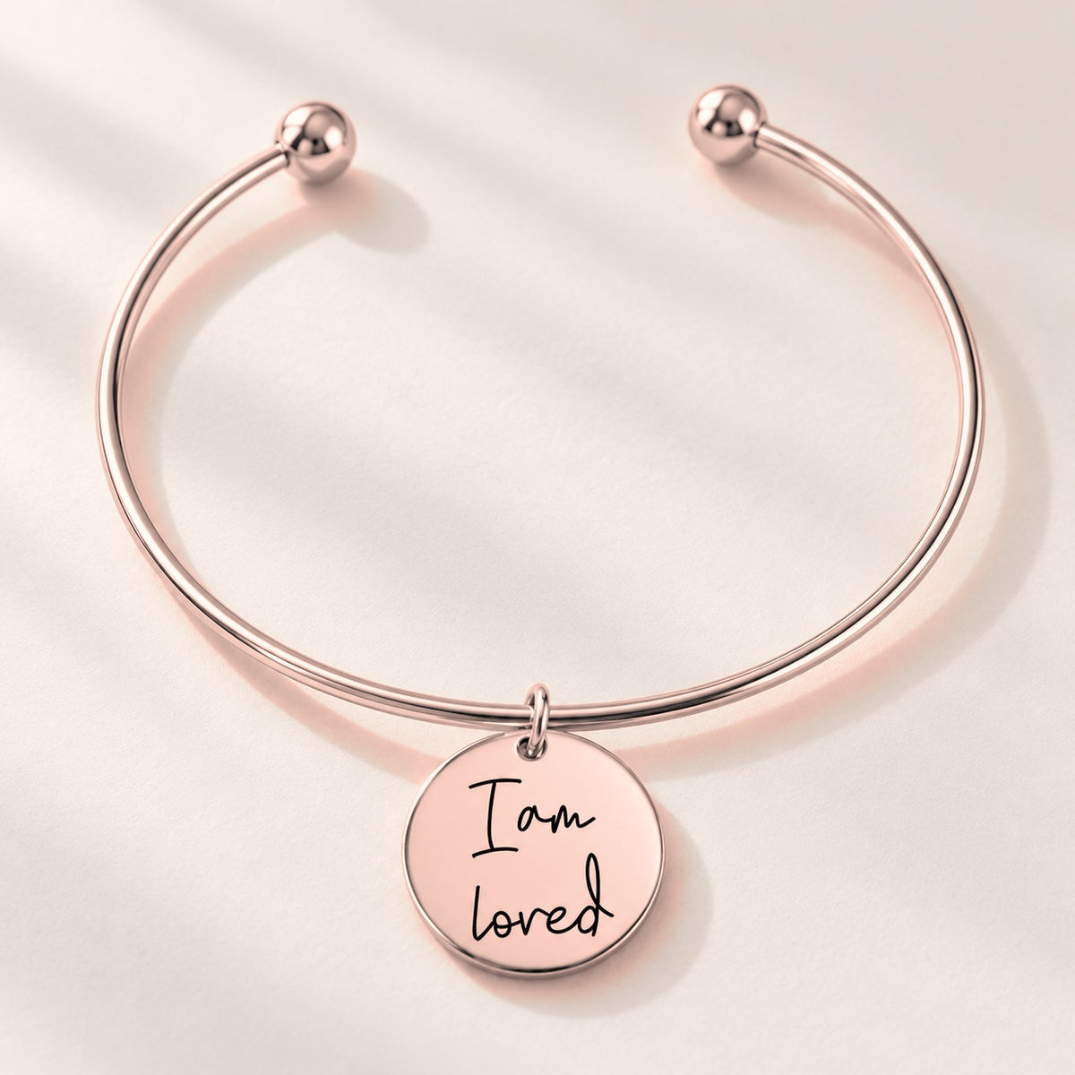 Bracelet jonc Médaille Affirmations Personnalisée, finition or rose, avec détail du bracelet et de ses attaches.