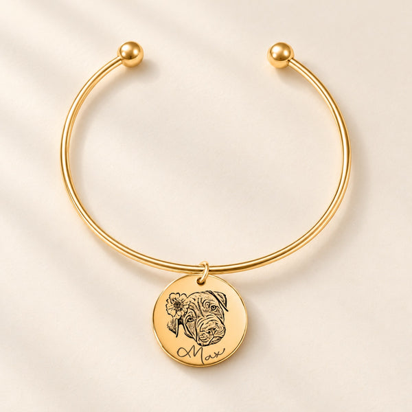 Bracelet jonc doré gravé du portrait de Max avec une fleur sur fond ivoire.