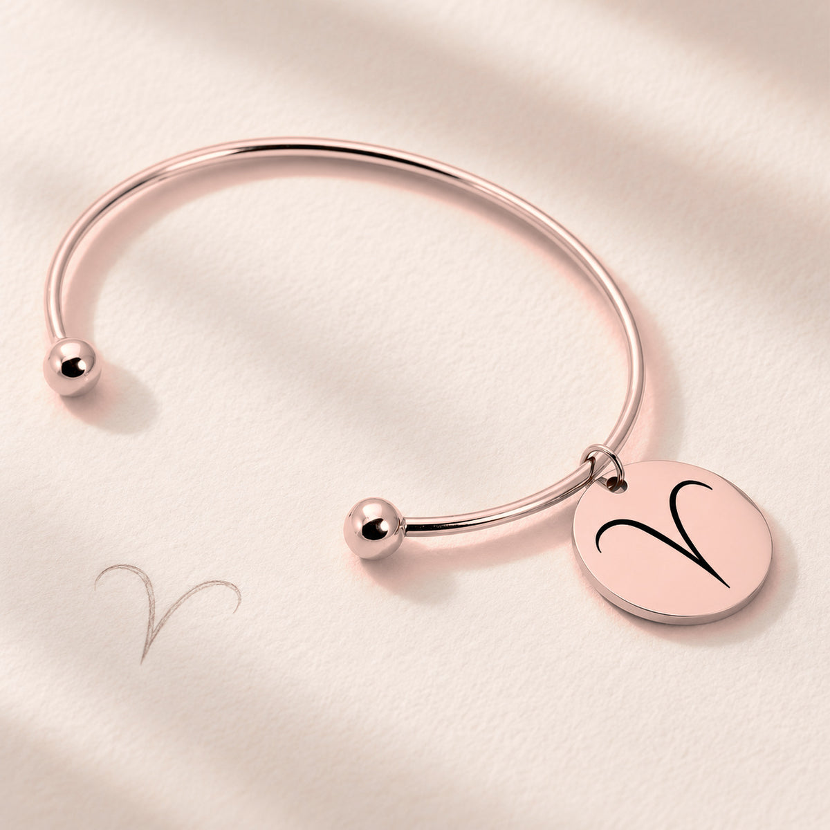 Bracelet Jonc Zodiaque, finition or rose, près d’un croquis au crayon.