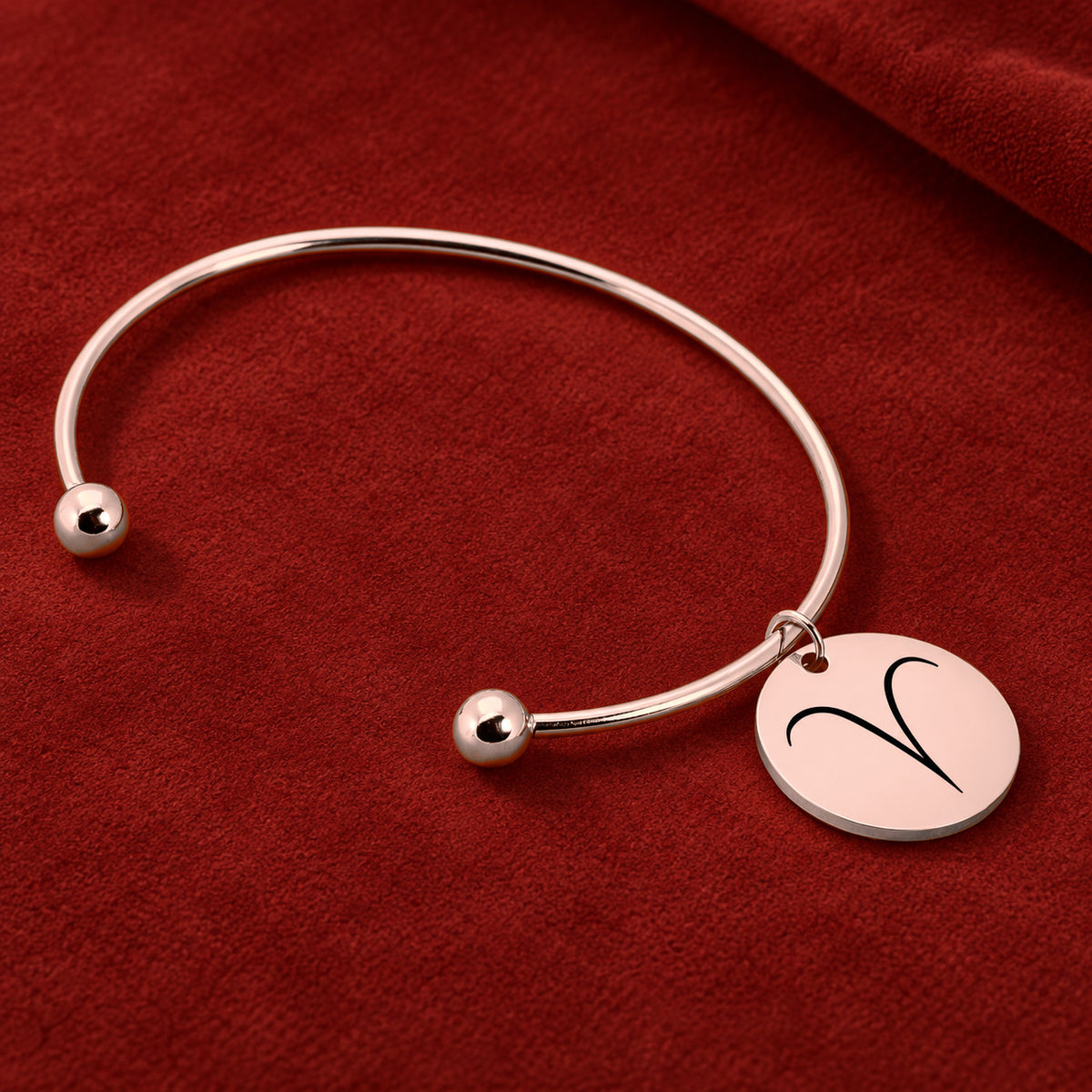 Bracelet Jonc Zodiaque, finition or rose, sur fond rouge sanguine.