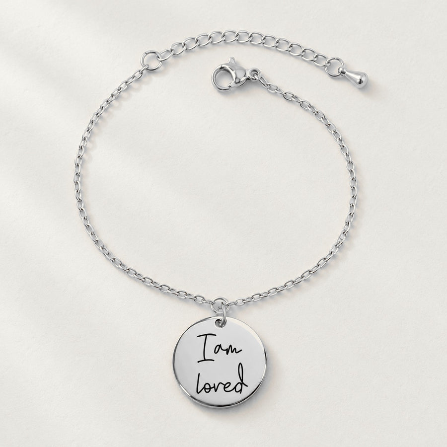 Bracelet Médaille Affirmations Personnalisée, finition argentée, sur fond ivoire.