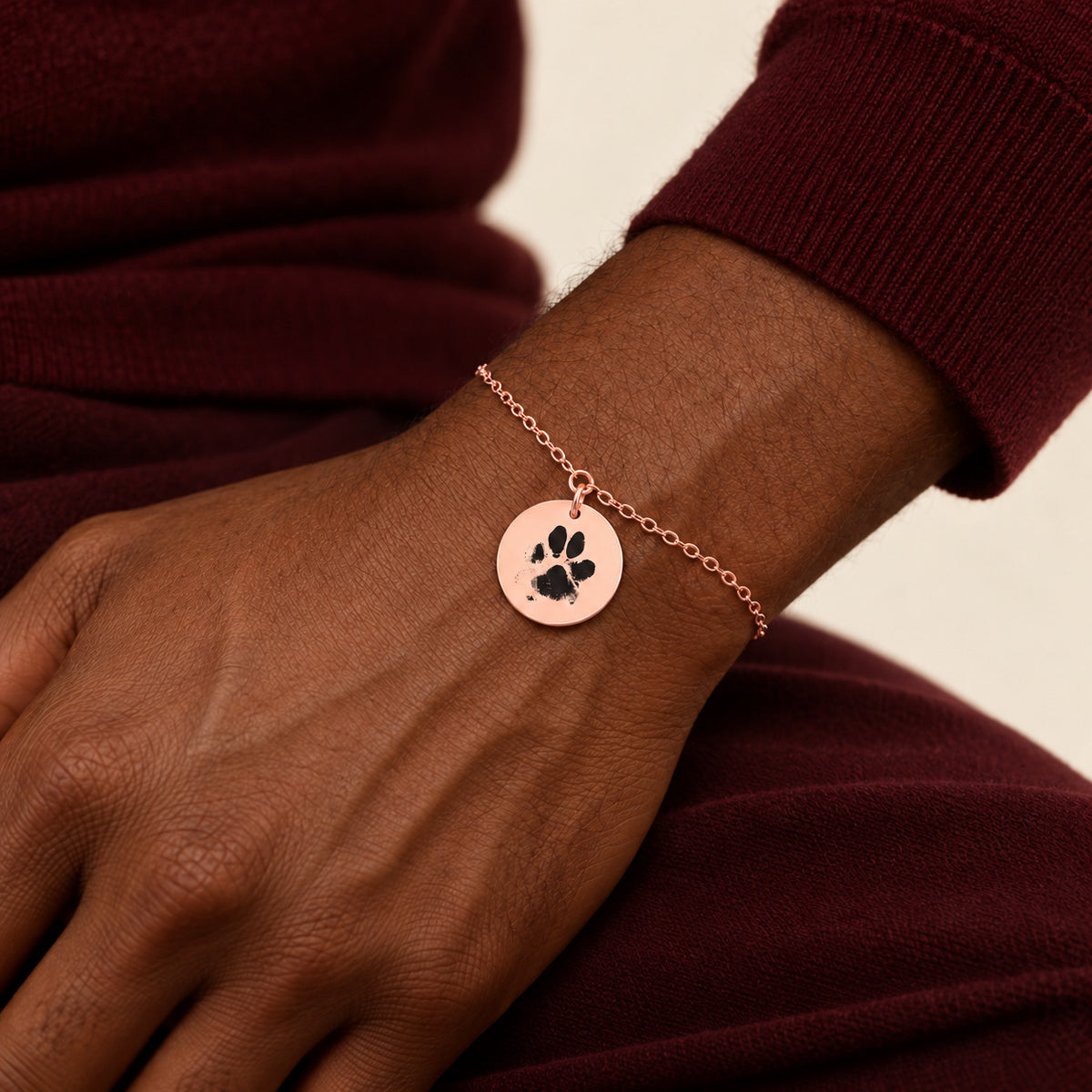 Bracelet personnalisé avec empreinte de patte, finition or rose, porté au poignet.