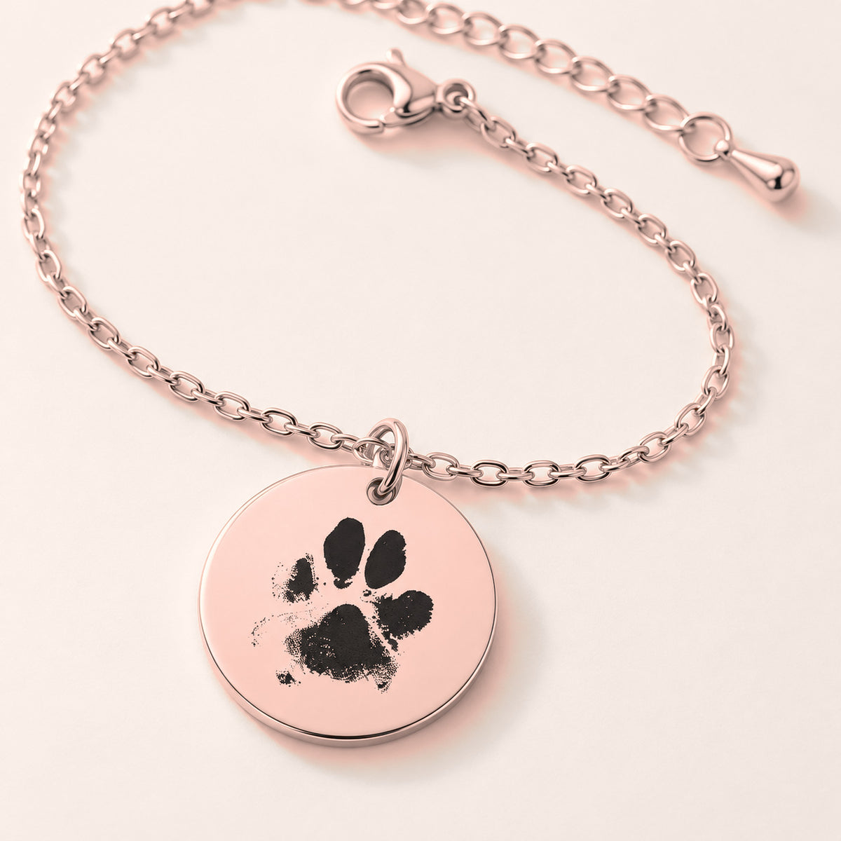 Bracelet personnalisé avec empreinte de patte, finition or rose, en gros plan sur la gravure.