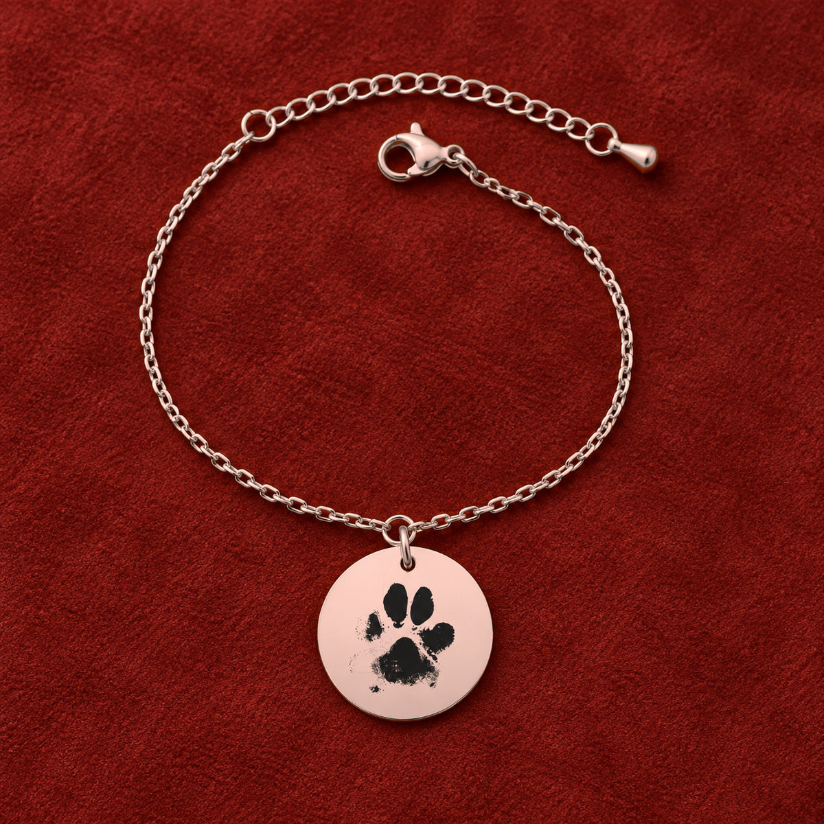 Bracelet personnalisé avec empreinte de patte, finition or rose, sur fond rouge sanguine.