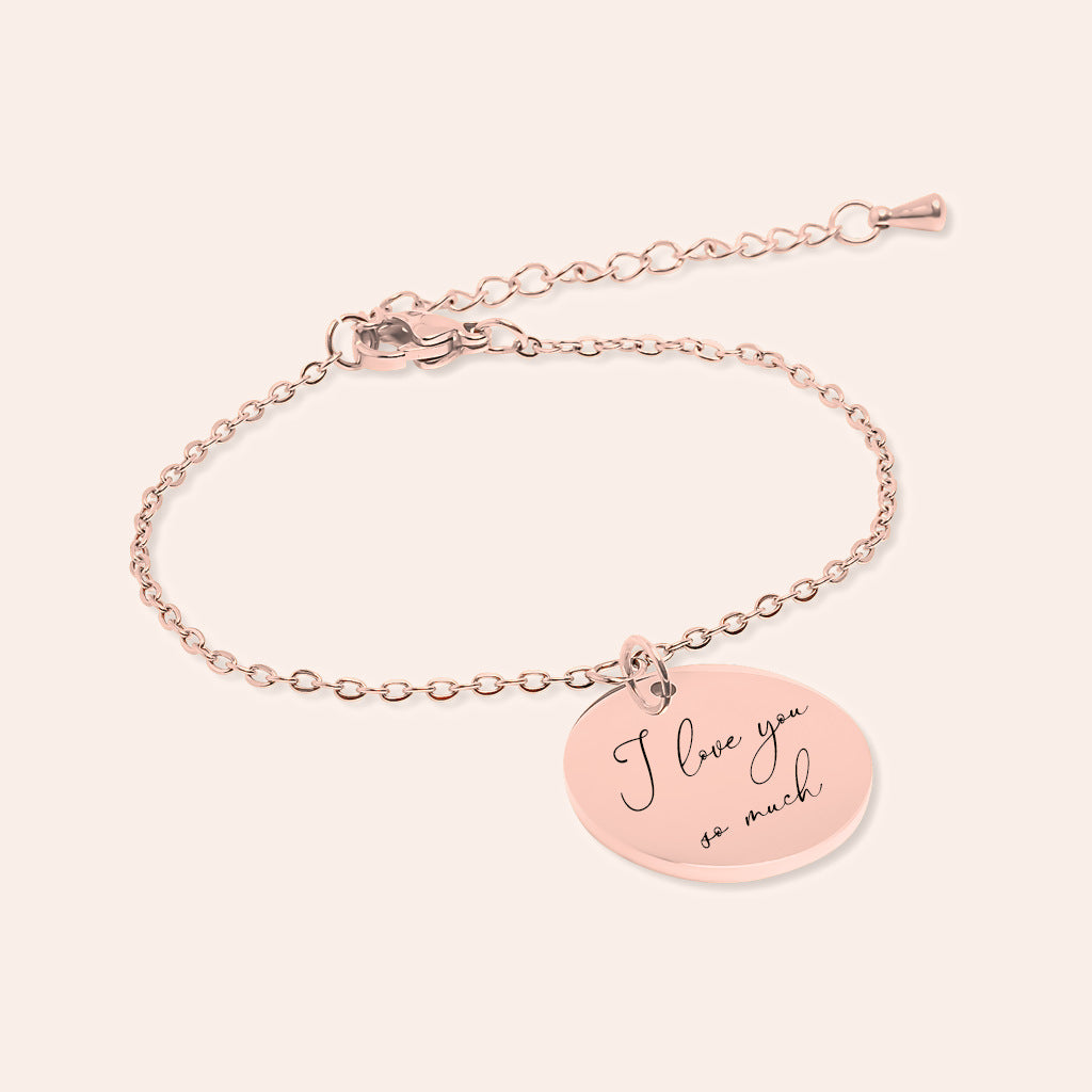 Bracelet Personnalisé avec message écrit, finition or rose, sur fond ivoire.