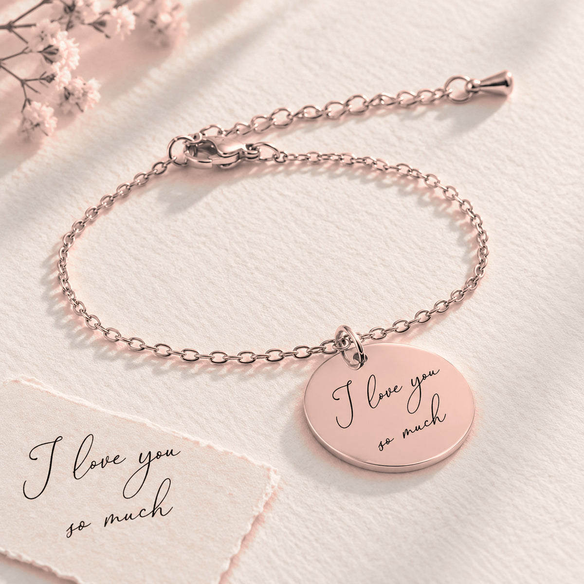 Bracelet Personnalisé avec message écrit, finition or rose, près d’un croquis au crayon.
