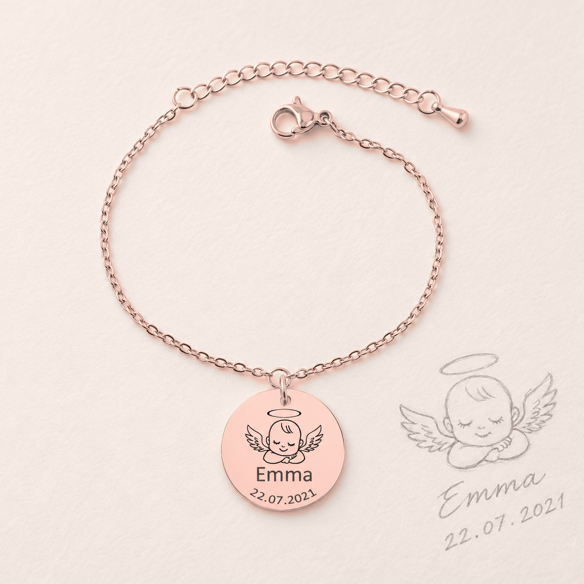 Bracelet Personnalisé Bébé Ange, finition or rose, près d’un croquis au crayon.