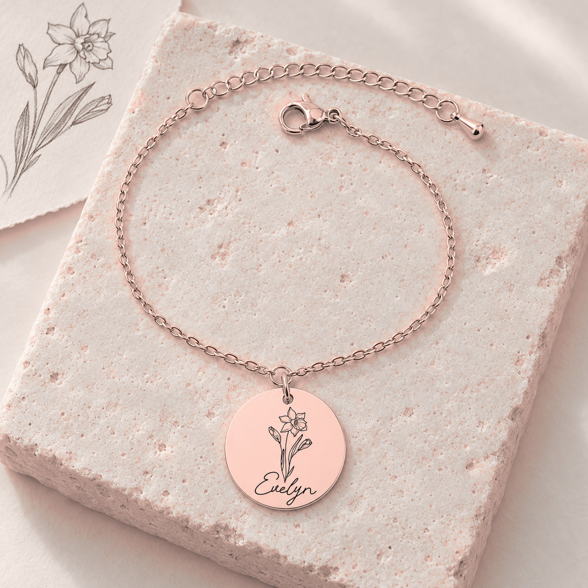 Bracelet Personnalisé de Naissance avec Fleur & Prénom, finition or rose, sur une pierre claire.