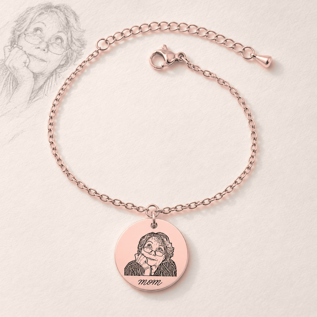 Bracelet Personnalisé Gravé avec Photo, finition or rose, près d’un croquis au crayon.