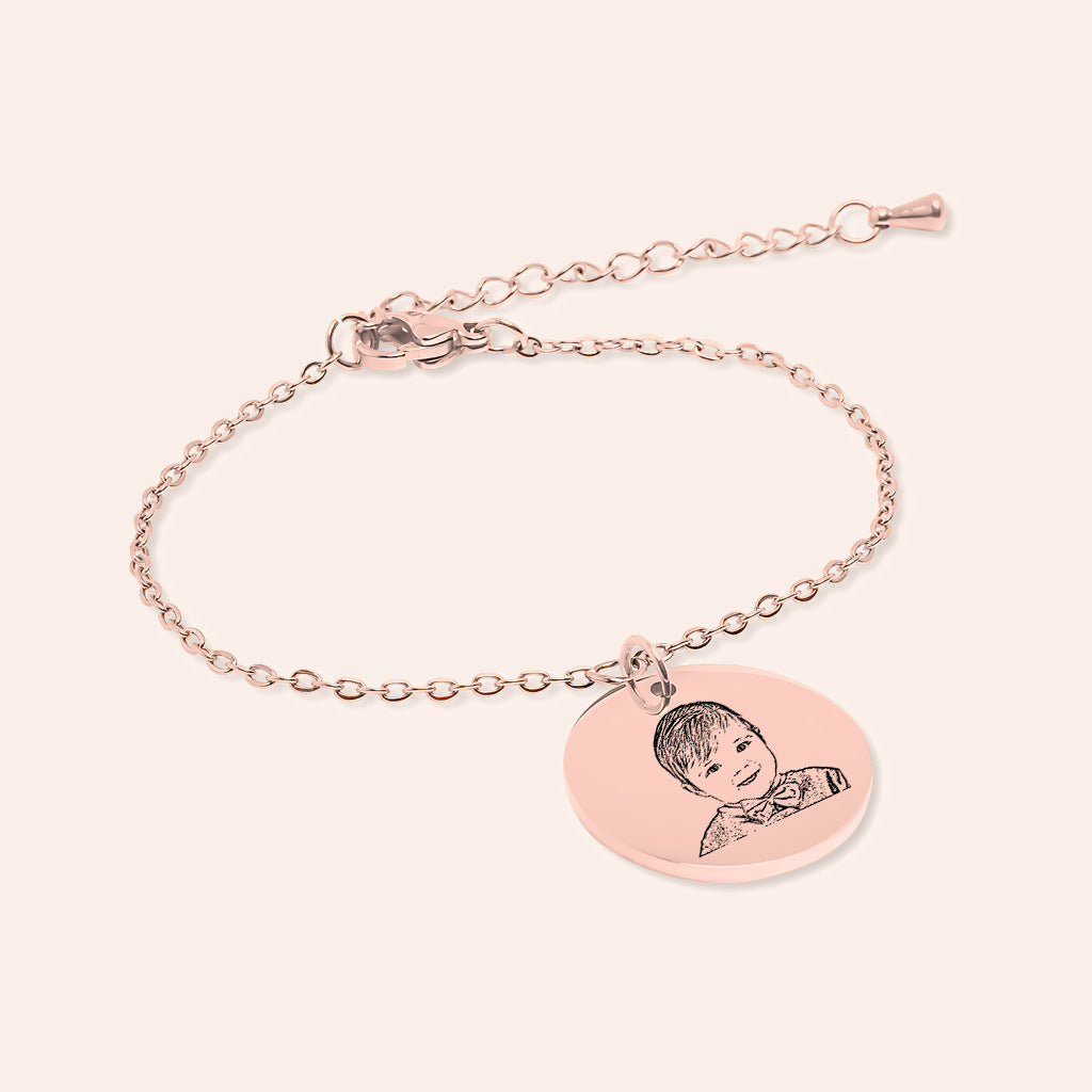 Bracelet Personnalisé Gravé avec Portrait de bébé, finition or rose, sur fond ivoire.