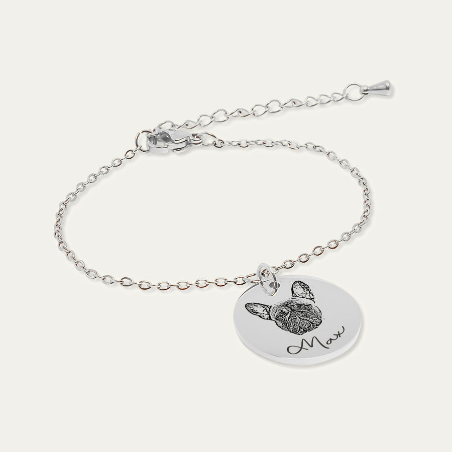 Bracelet chaîne en finition argentée, médaille gravée du portrait d’un bouledogue français et du prénom Max, sur fond ivoire.