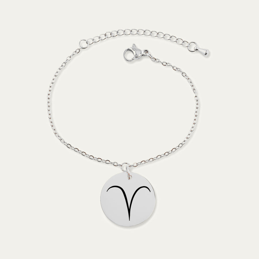 Bracelet chaîne en finition argentée, médaille gravée du signe Bélier, sur fond ivoire.