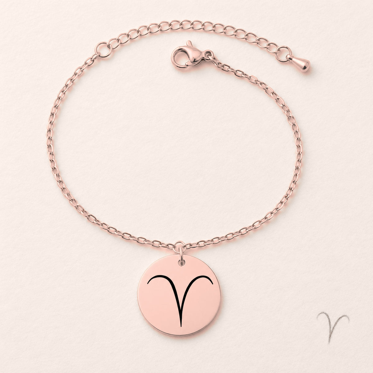 Bracelet Signe Astrologique, finition or rose, près d’un croquis au crayon.