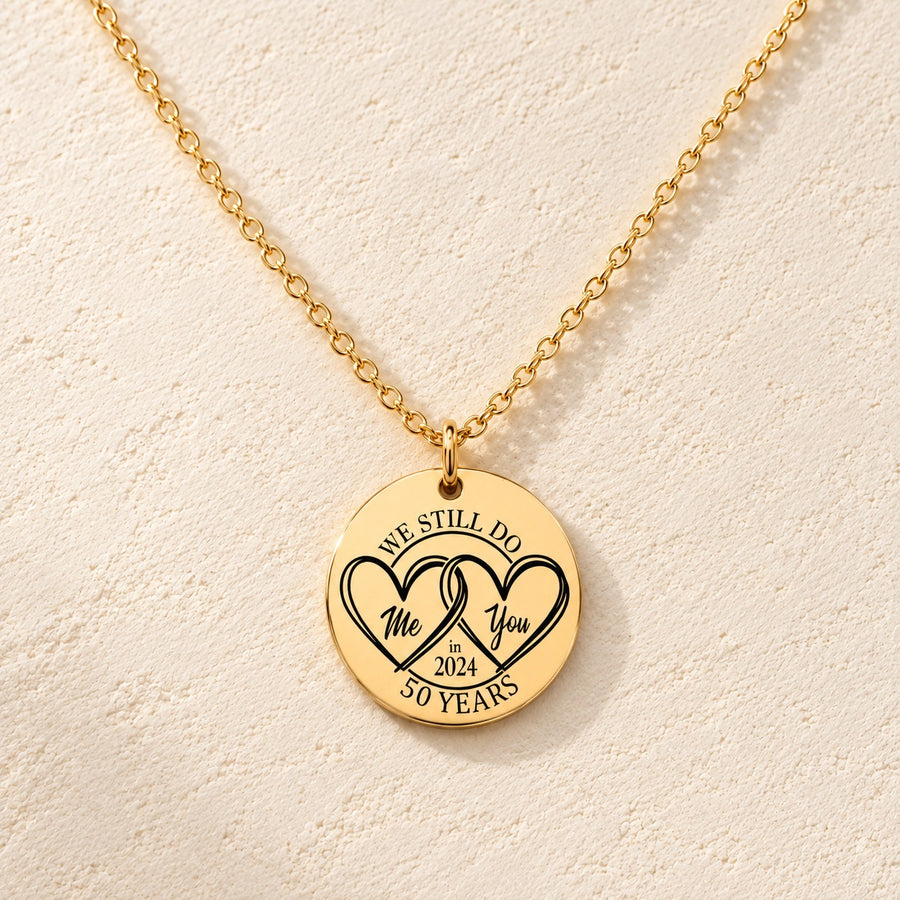Collier Anniversaire de Mariage 50 ans personnalisé doré, médaille ronde gravée avec deux cœurs et inscription « 50 YEARS », sur fond ivoire.