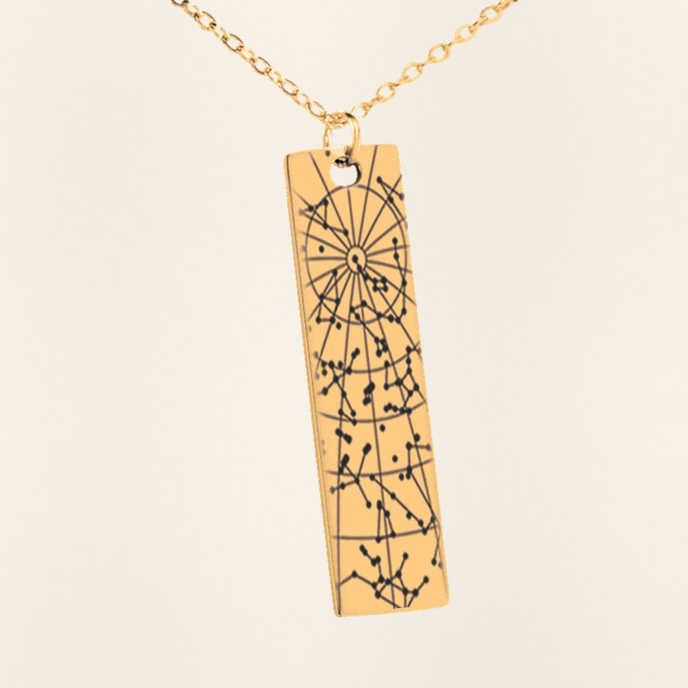 Collier Carte des Étoiles Personnalisé (Barre Verticale) en finition dorée, exemple de gravure sur fond ivoire texturé.