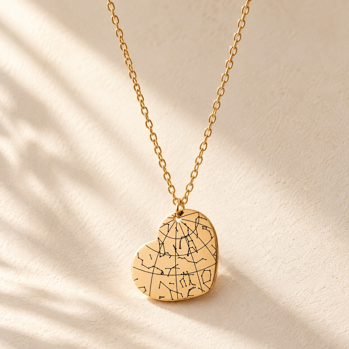 Collier Carte des Étoiles doré, pendentif en forme de cœur avec carte des étoiles sur fond ivoire.