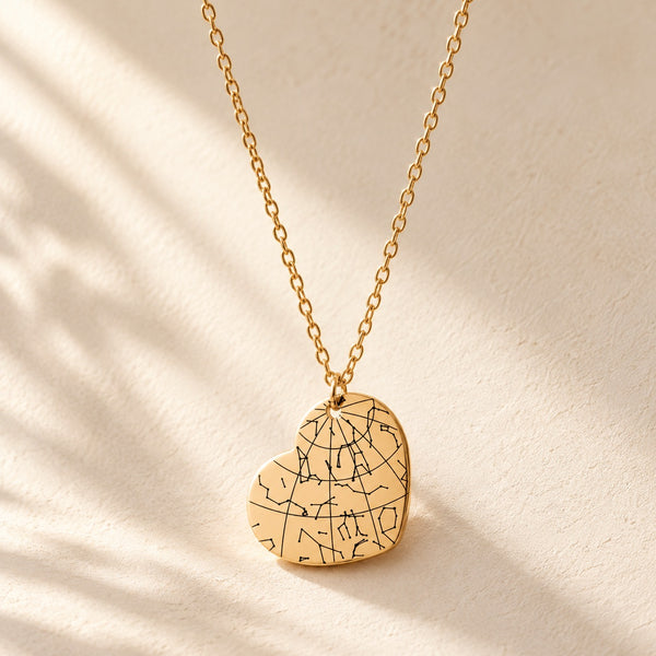 Collier Carte des Étoiles doré, pendentif en forme de cœur avec carte des étoiles sur fond ivoire.