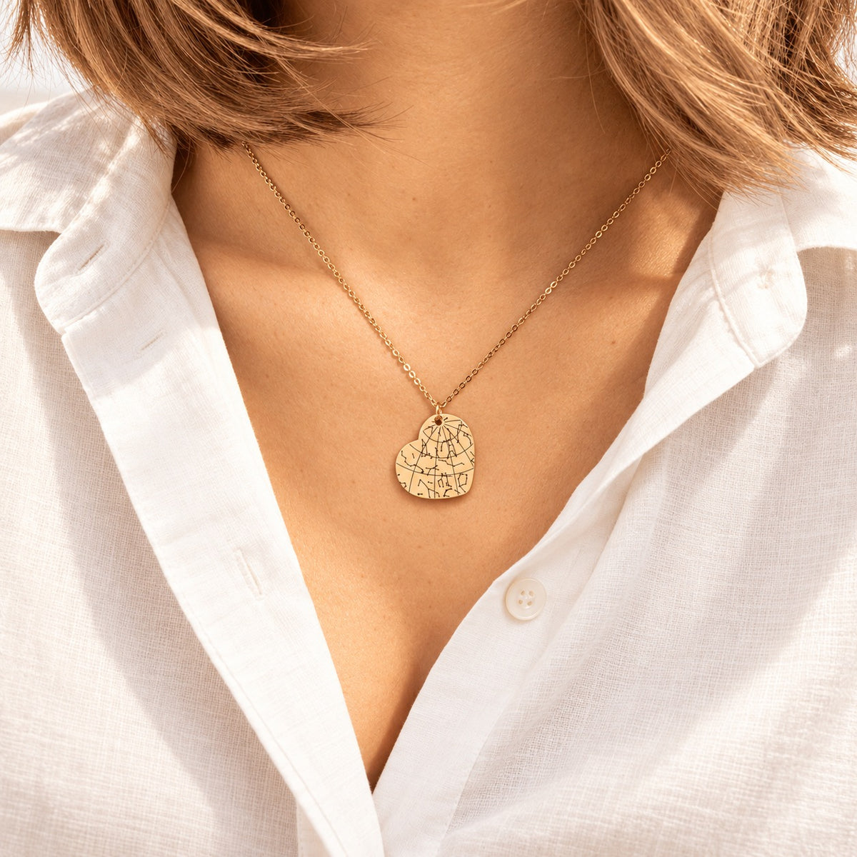 Collier Carte des Étoiles doré porté au cou, détail du pendentif gravé.