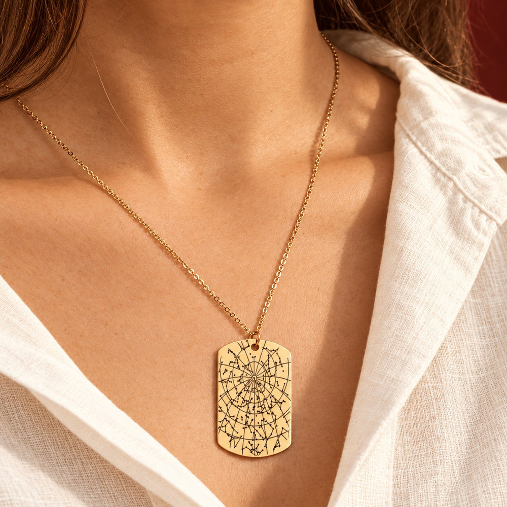 Collier Carte des Étoiles doré porté au cou, détail du pendentif gravé.