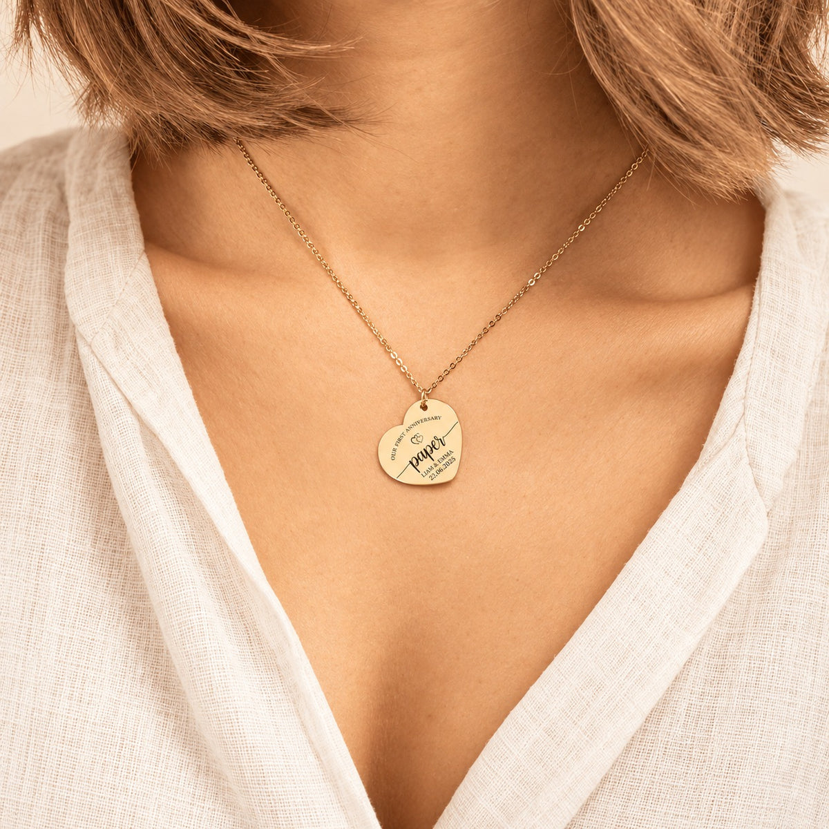 Collier cœur premier anniversaire de mariage doré porté au cou, avec pendentif en forme de cœur gravé.