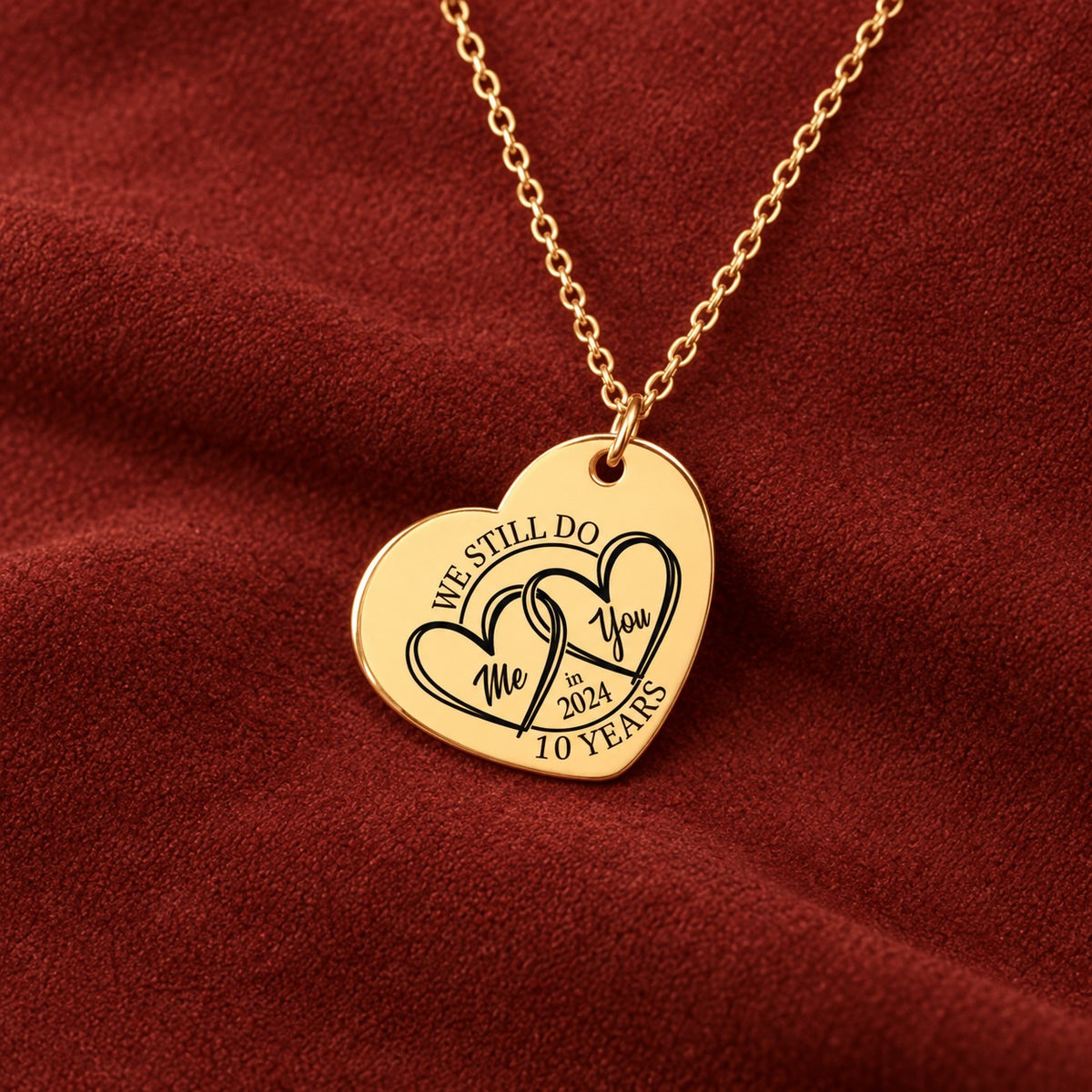 Médaille en cœur dorée gravée avec deux cœurs et inscription « 10 YEARS », sur suédine rouge sanguine.