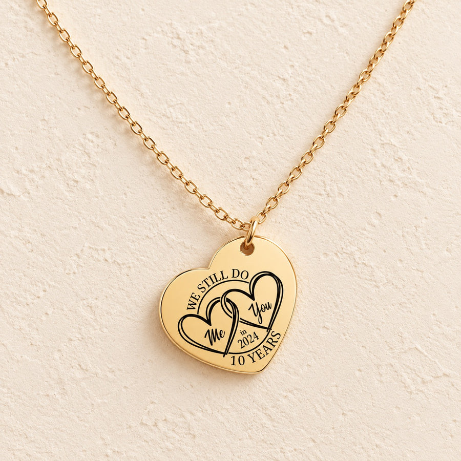 Collier cœur anniversaire de mariage 10 ans doré, médaille en cœur gravée avec deux cœurs et inscription « 10 YEARS », sur fond ivoire.