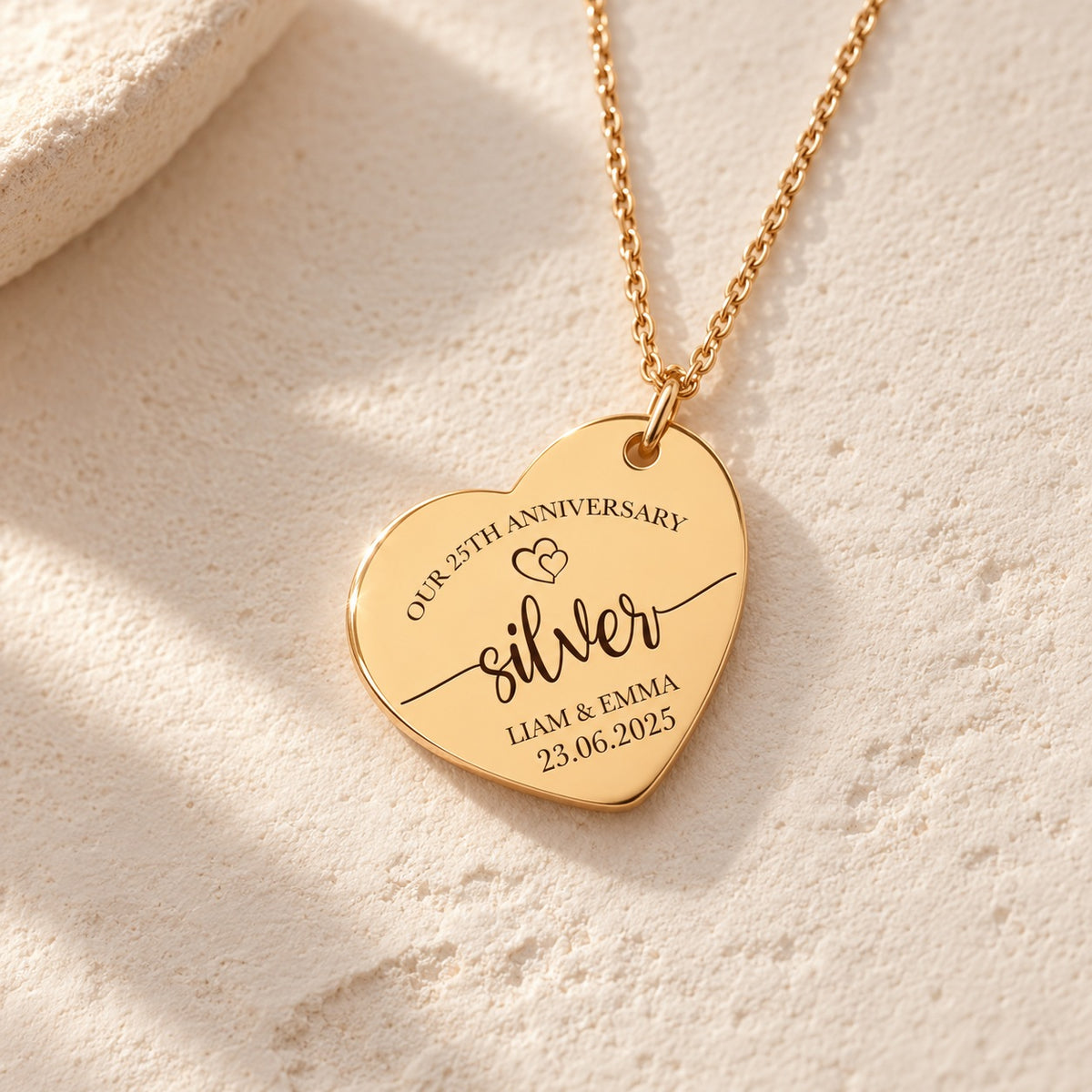 Détail de la médaille en cœur dorée gravée avec inscription « silver », prénoms Liam et Emma et date 23.06.2025.