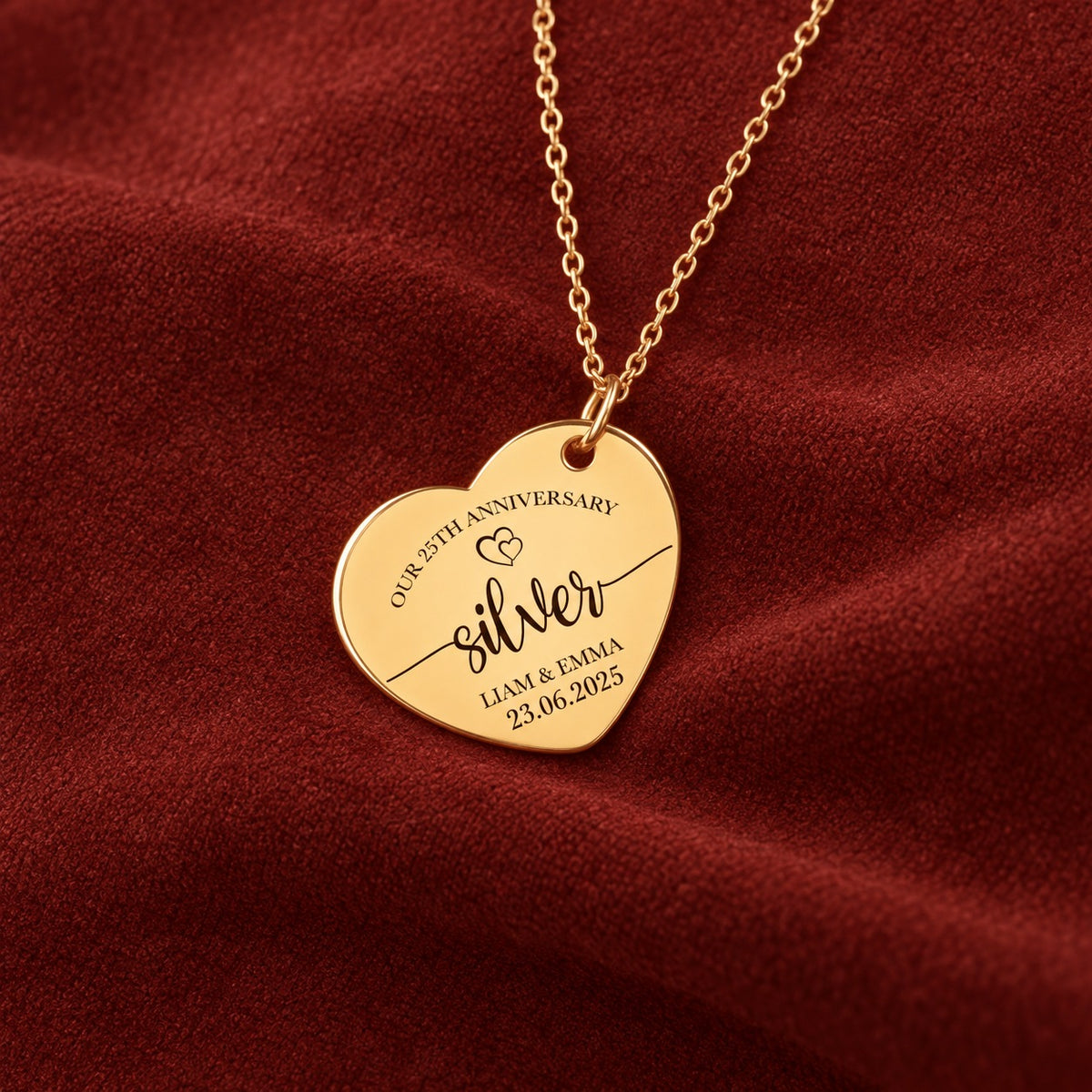 Médaille en cœur dorée gravée avec inscription « silver », prénoms Liam et Emma et date 23.06.2025, sur suédine rouge sanguine.