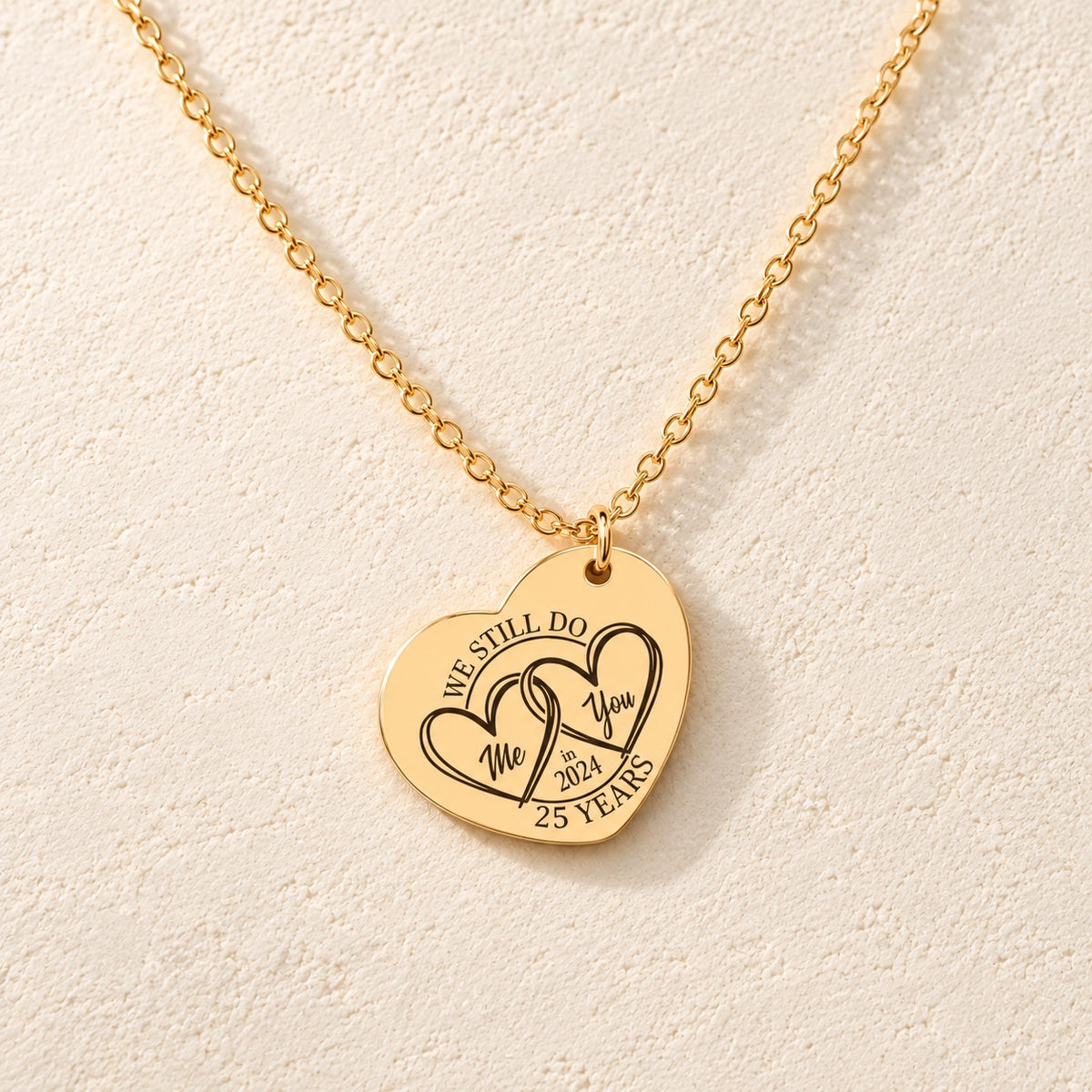 Collier cœur noces d’argent 25 ans doré, médaille en cœur gravée avec deux cœurs et inscription « 25 YEARS », sur fond ivoire.