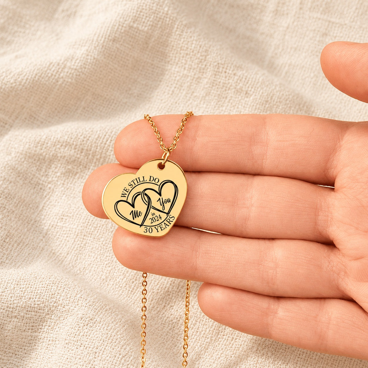Collier Coeur Anniversaire de Mariage 30 ans doré tenu en main, détail de la gravure.
