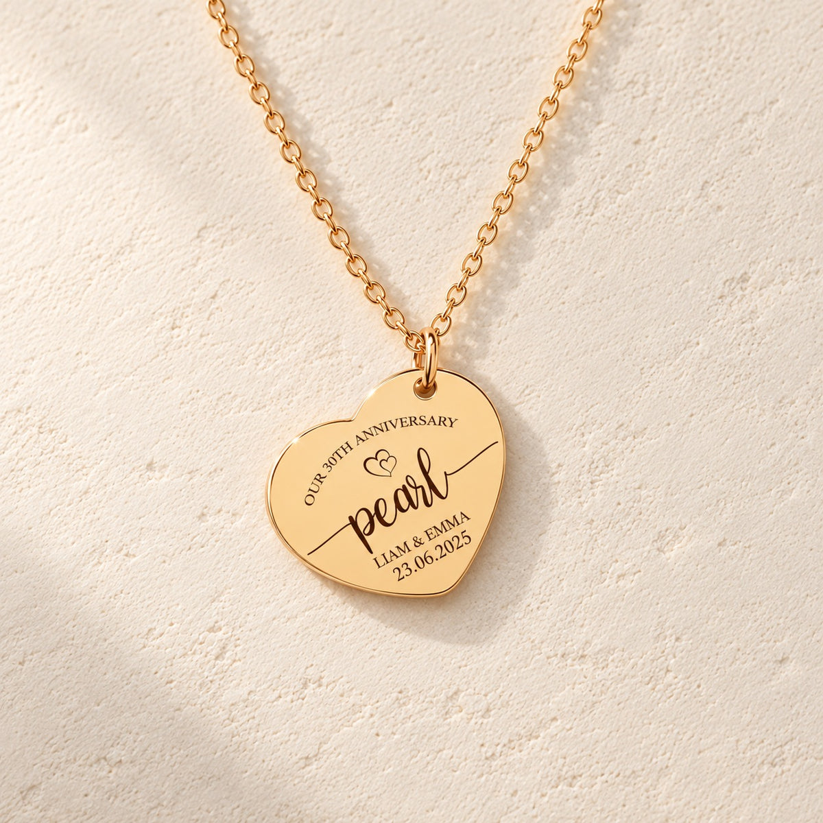 Détail de la médaille en cœur dorée avec inscription « pearl », prénoms Liam et Emma et date 23.06.2025.