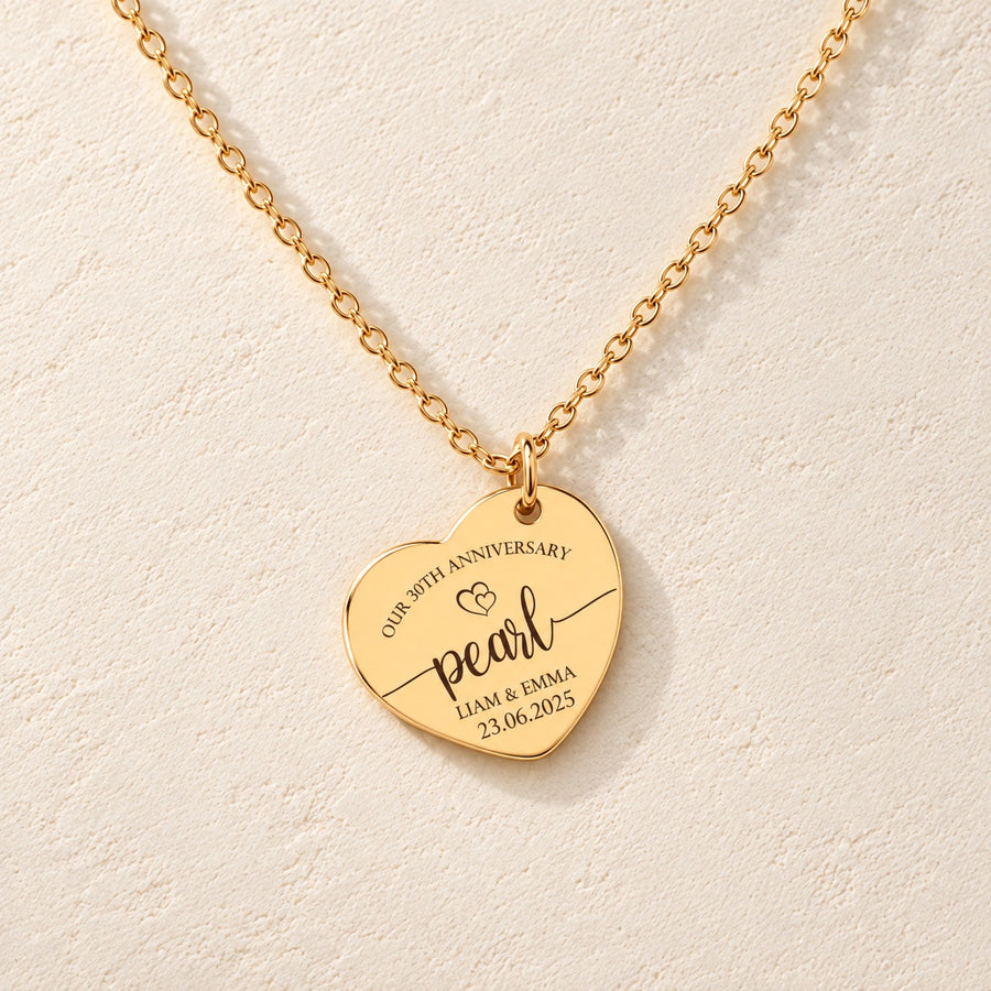 Collier Coeur Anniversaire de Mariage 30 ans doré, médaille en cœur gravée avec inscription « pearl », prénoms Liam et Emma et date 23.06.2025, sur fond ivoire.
