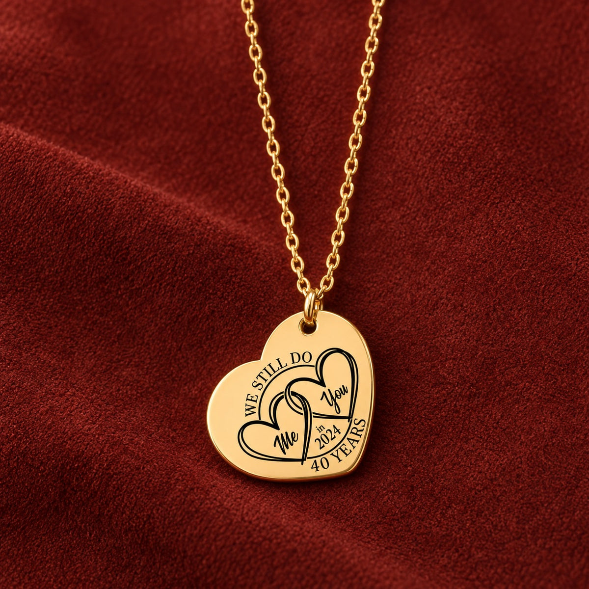 Collier cœur anniversaire de mariage 40 ans doré avec deux cœurs entrelacés et inscription « 40 YEARS », sur suédine rouge sanguine.