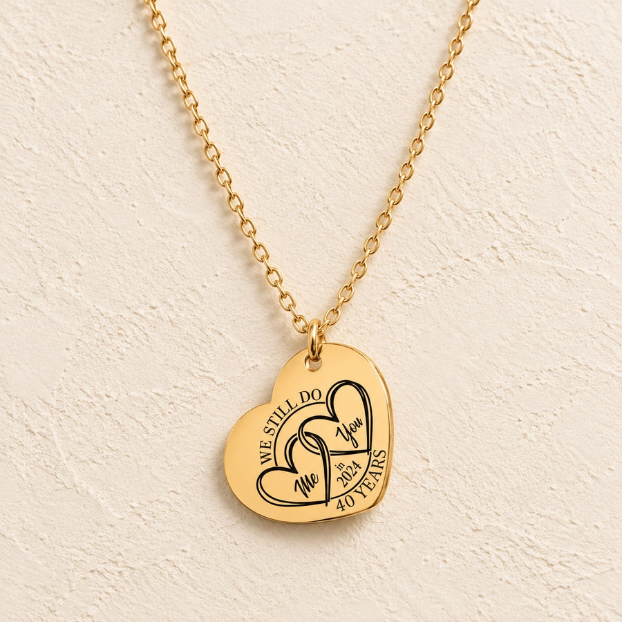 Collier cœur anniversaire de mariage 40 ans doré avec deux cœurs entrelacés et inscription « 40 YEARS », sur fond ivoire.
