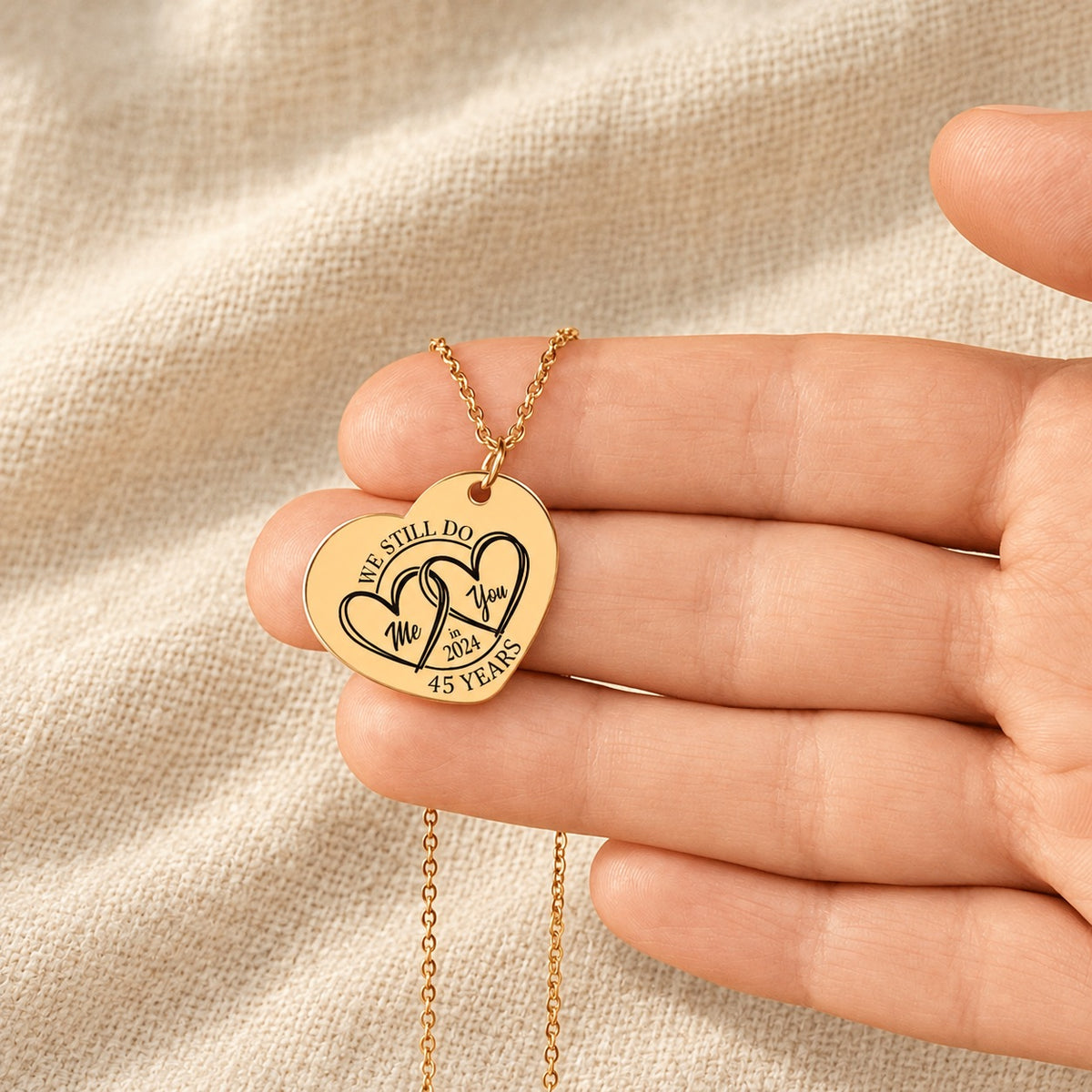 Collier Coeur Anniversaire de Mariage 45 ans doré tenu en main, détail de la gravure.