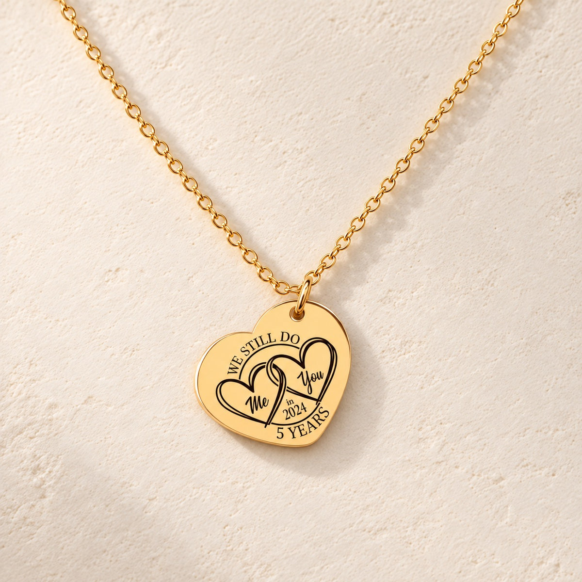 Collier Coeur Anniversaire de Mariage 5 ans doré, médaille en cœur gravée avec deux cœurs et inscription « 5 YEARS », sur fond ivoire.