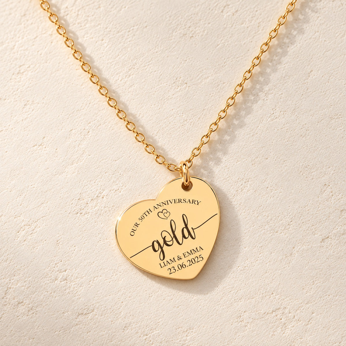 Détail de la médaille en cœur dorée avec inscription « gold », prénoms Liam et Emma et date 23.06.2025.