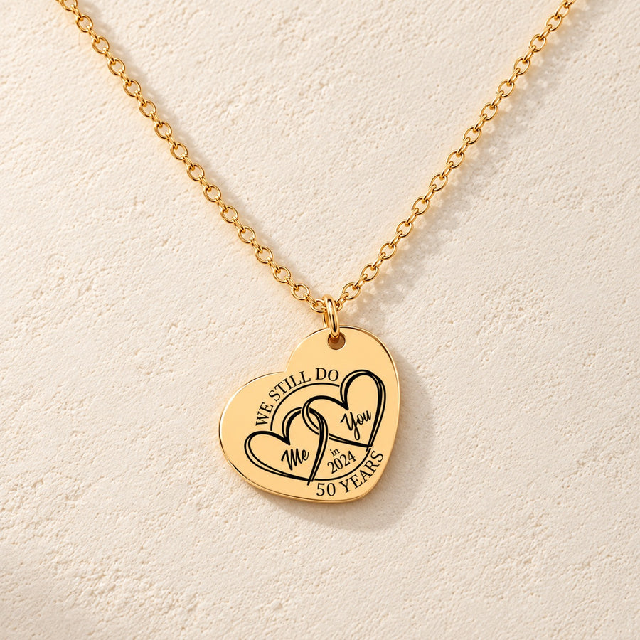 Collier Coeur Anniversaire de Mariage 50 ans doré, médaille en cœur gravée avec deux cœurs et inscription « 50 YEARS », sur fond ivoire.