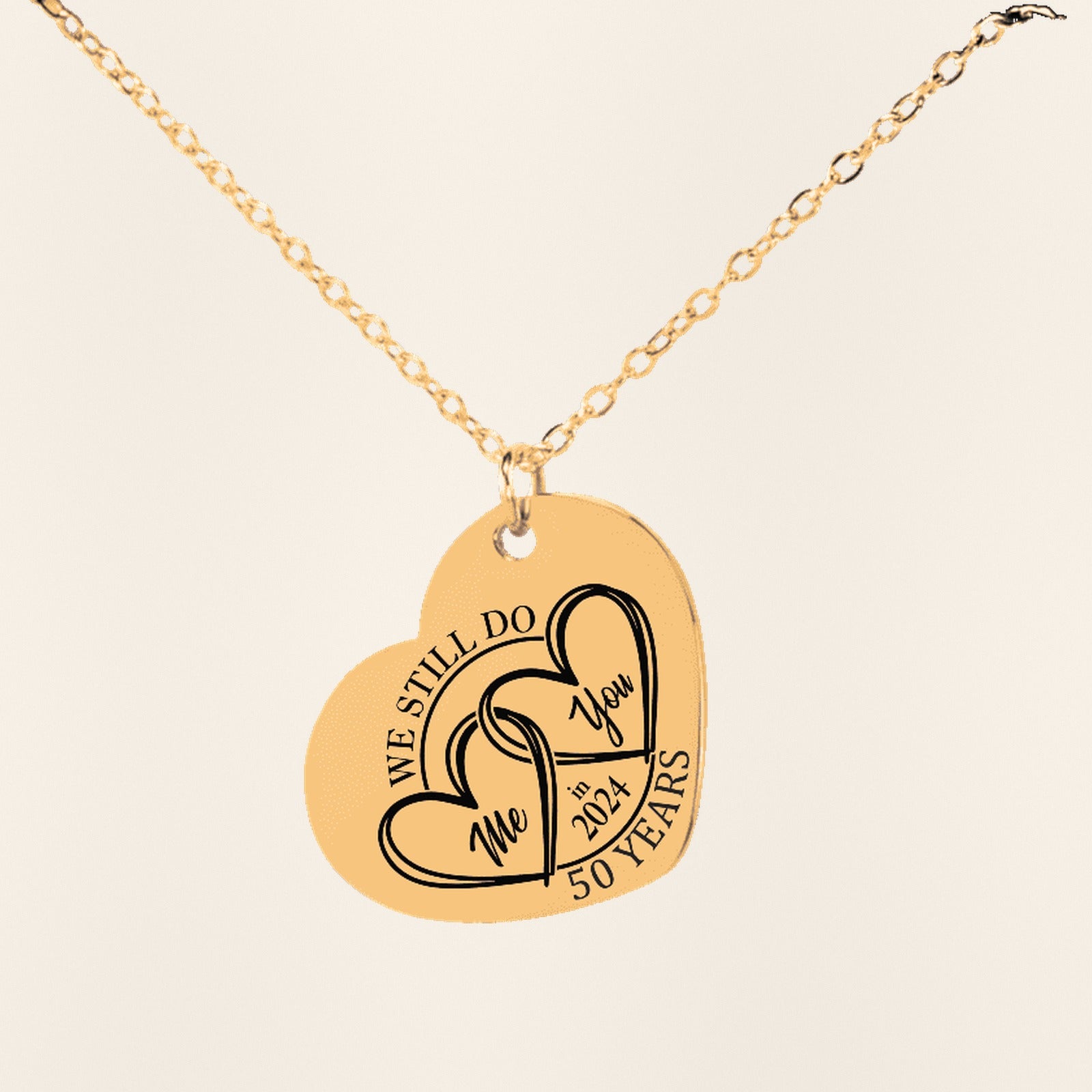 Collier Coeur Anniversaire de Mariage 50 ans (noces d'or) en finition dorée, exemple de gravure sur fond ivoire texturé.